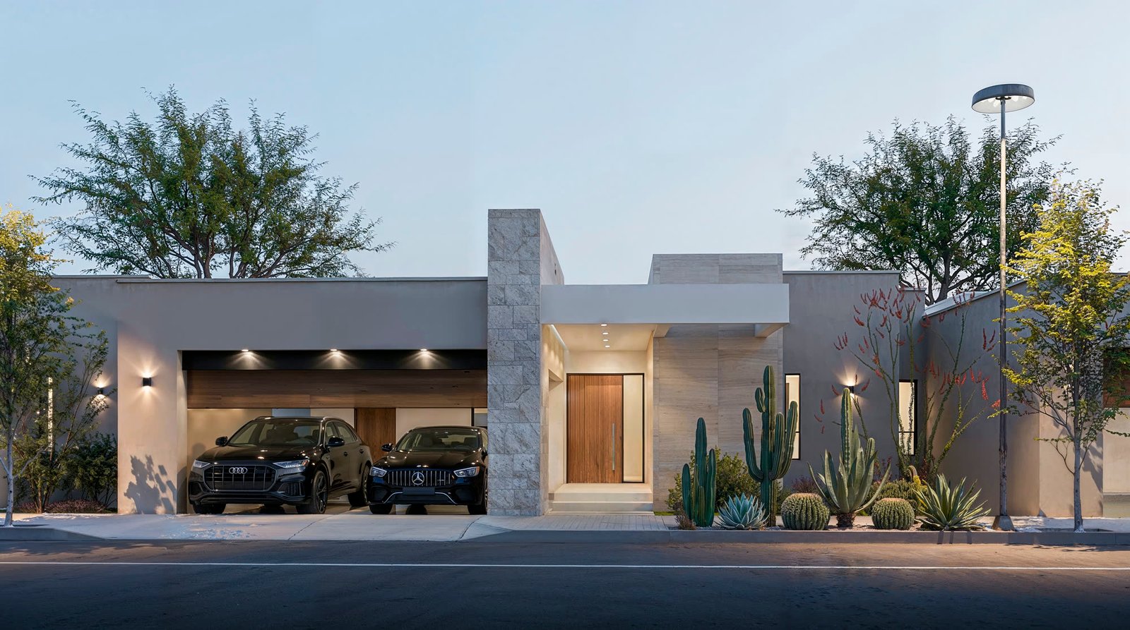 Fachada del Modelo Dune al anochecer: una sola planta, cochera techada con dos autos, acceso de madera y jardín de cactáceas y agaves.